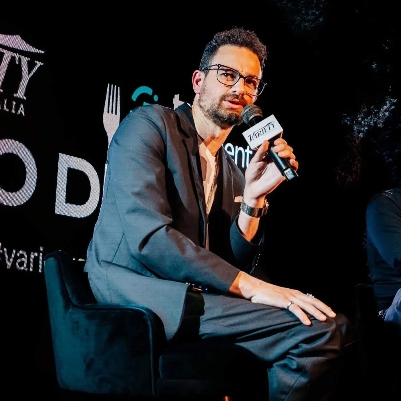 Luke Girgis on stage with a microphone